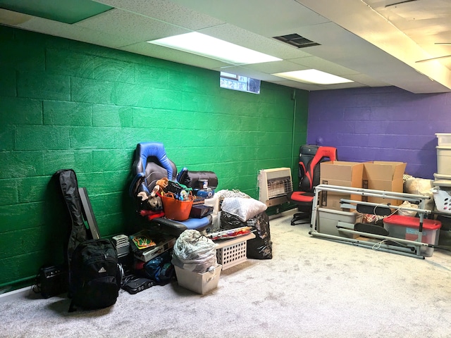 interior space with concrete block wall, visible vents, and carpet flooring