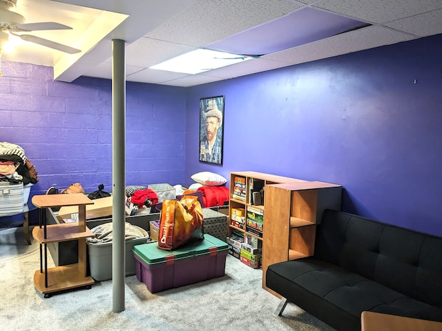 game room featuring carpet, a drop ceiling, ceiling fan, and concrete block wall