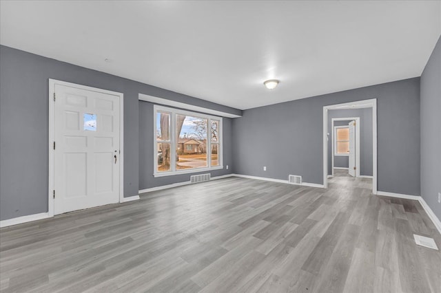 interior space featuring visible vents, light wood-style flooring, and baseboards