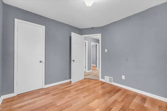 unfurnished bedroom with light wood-style flooring, visible vents, and baseboards