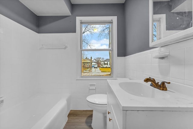 full bath featuring tile walls, toilet, wainscoting, vanity, and wood finished floors