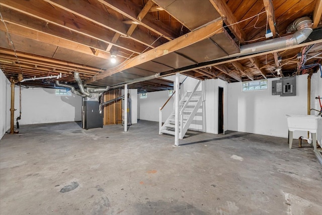 below grade area with heating unit, water heater, stairway, a sink, and electric panel