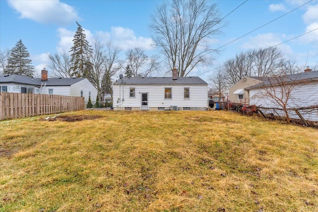 back of house featuring a lawn, a chimney, and fence