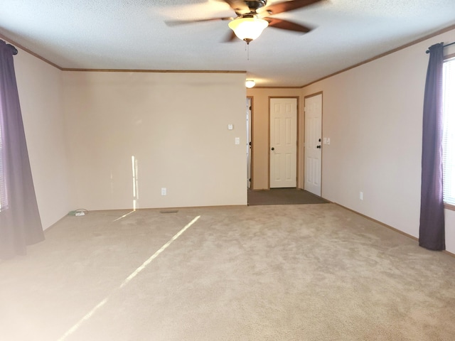 carpeted empty room with a textured ceiling, ornamental molding, and a ceiling fan