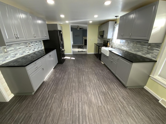 kitchen featuring freestanding refrigerator, gray cabinets, dark countertops, and baseboards