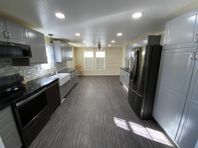 kitchen with dark countertops, gray cabinetry, black appliances, pendant lighting, and a sink