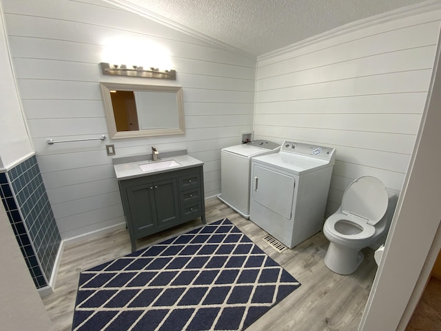 bathroom featuring washer and clothes dryer, wood finished floors, vaulted ceiling, a textured ceiling, and vanity