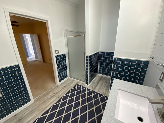 bathroom with wainscoting, tile walls, and wood finished floors