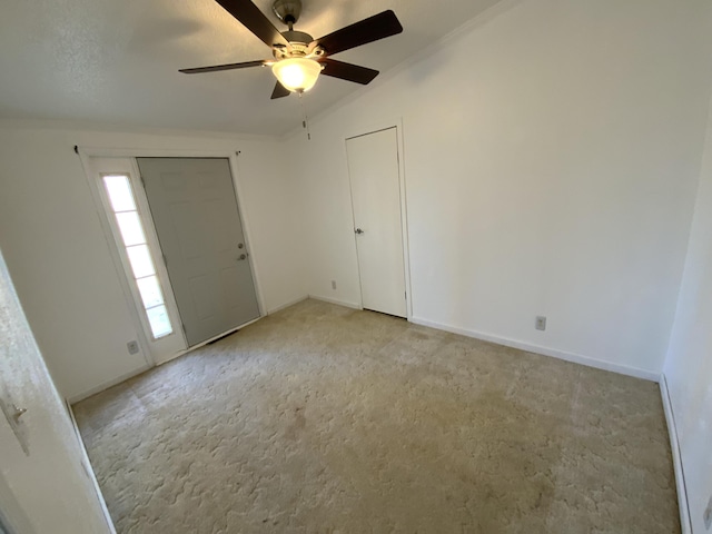 entrance foyer featuring light carpet, ornamental molding, and baseboards