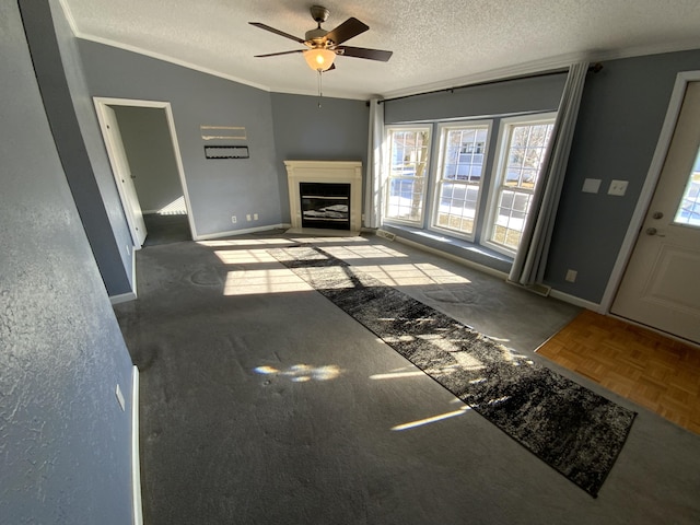 living room featuring baseboards, a glass covered fireplace, lofted ceiling, crown molding, and a textured ceiling