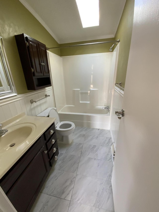 bathroom featuring marble finish floor, a wainscoted wall, toilet, ornamental molding, and tub / shower combination