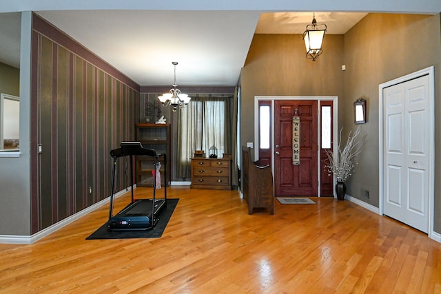 entryway with an inviting chandelier, baseboards, and wood finished floors