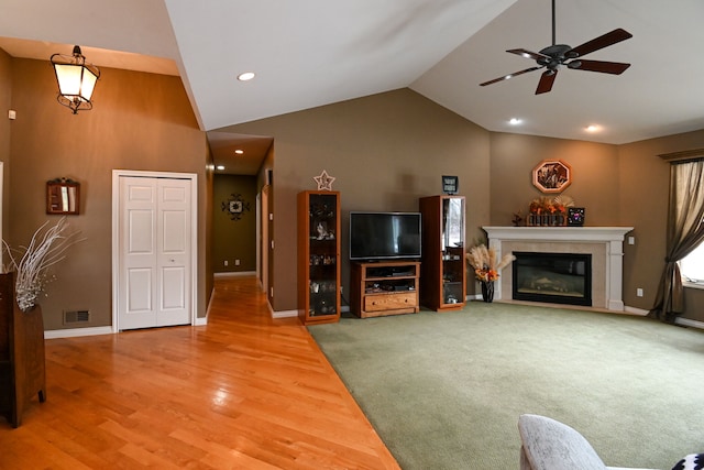 living room with baseboards, visible vents, wood finished floors, vaulted ceiling, and a fireplace