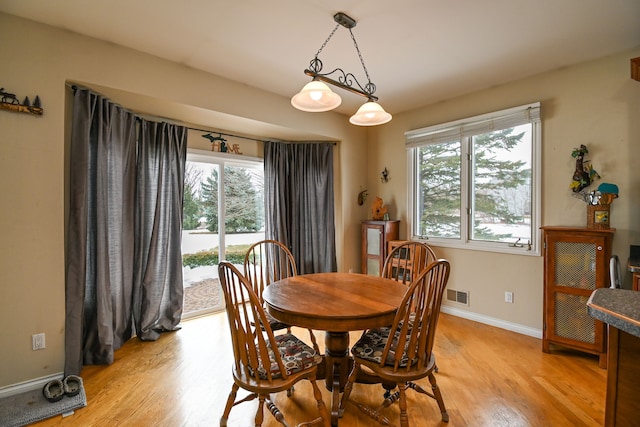 dining space with baseboards, visible vents, and light wood-style floors