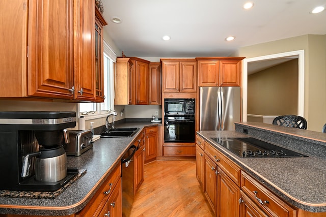 kitchen featuring dark countertops, brown cabinets, a sink, and black appliances