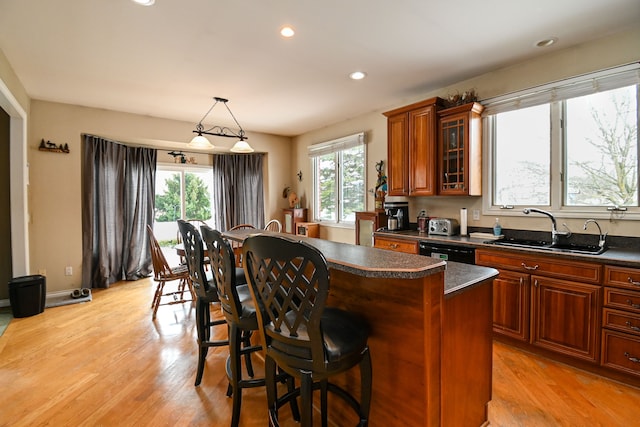 kitchen featuring a kitchen island, dark countertops, a sink, and dishwasher