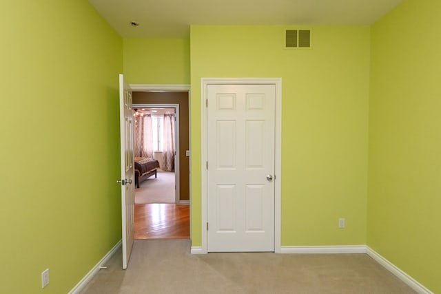 unfurnished bedroom with light carpet, visible vents, and baseboards