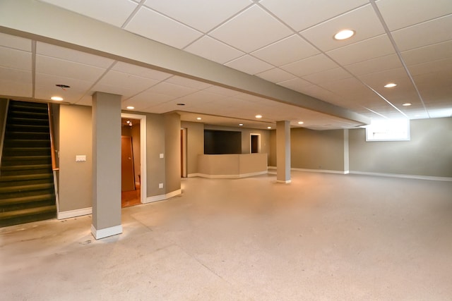 below grade area featuring a paneled ceiling, baseboards, stairway, and recessed lighting