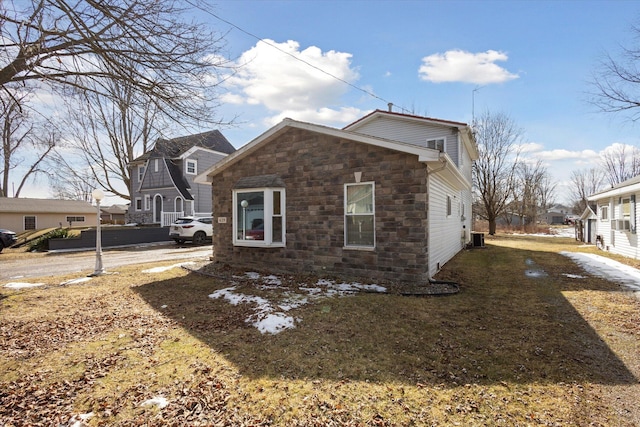 view of home's exterior featuring stone siding, central AC, and a residential view