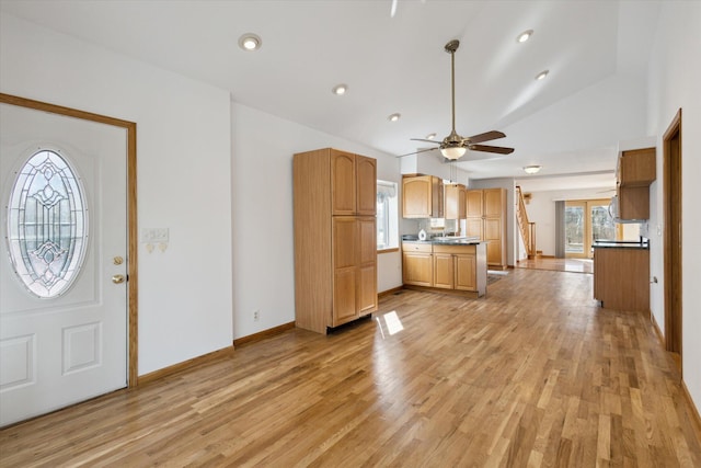 interior space featuring light countertops, a ceiling fan, vaulted ceiling, light wood-type flooring, and baseboards