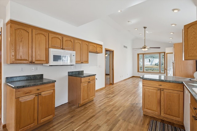 kitchen with brown cabinetry, dark countertops, and white microwave