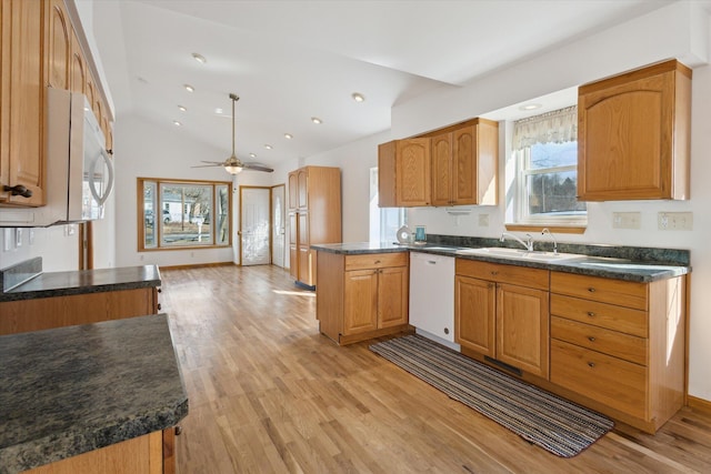 kitchen featuring dark countertops, white appliances, and a sink