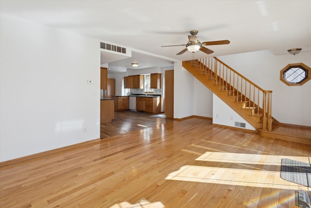 unfurnished living room with stairs, ceiling fan, light wood finished floors, and visible vents