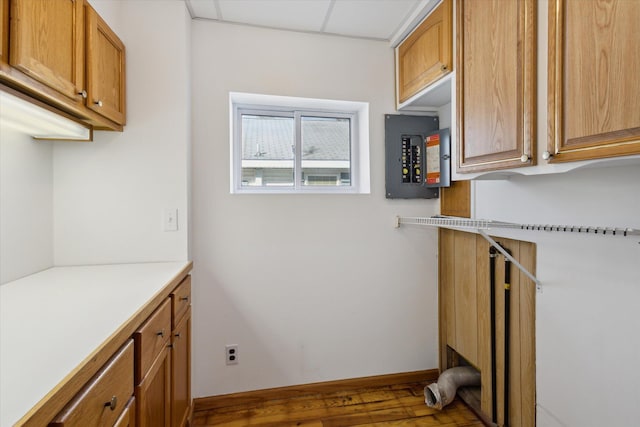 clothes washing area featuring dark wood-type flooring, electric panel, and baseboards