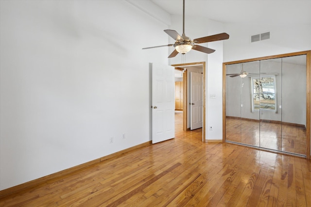 unfurnished bedroom featuring a closet, wood-type flooring, visible vents, vaulted ceiling, and baseboards