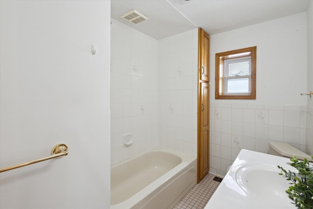 bathroom with visible vents, toilet, a sink, tile patterned flooring, and tile walls