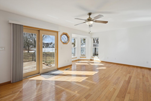 spare room with plenty of natural light, light wood-type flooring, a ceiling fan, and baseboards