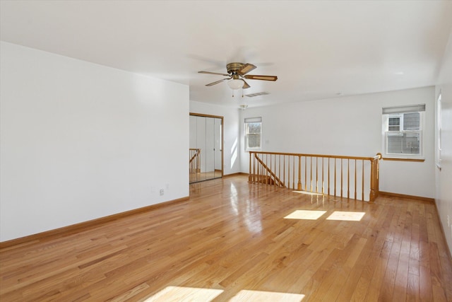 spare room with light wood-type flooring, visible vents, ceiling fan, and baseboards