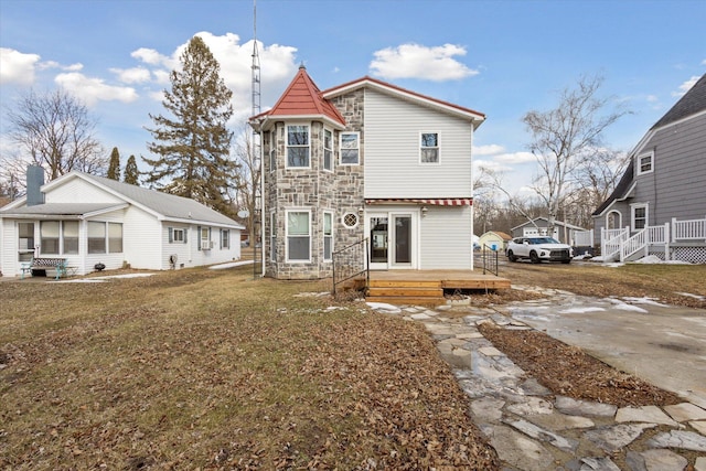 back of house featuring stone siding, a lawn, and a wooden deck