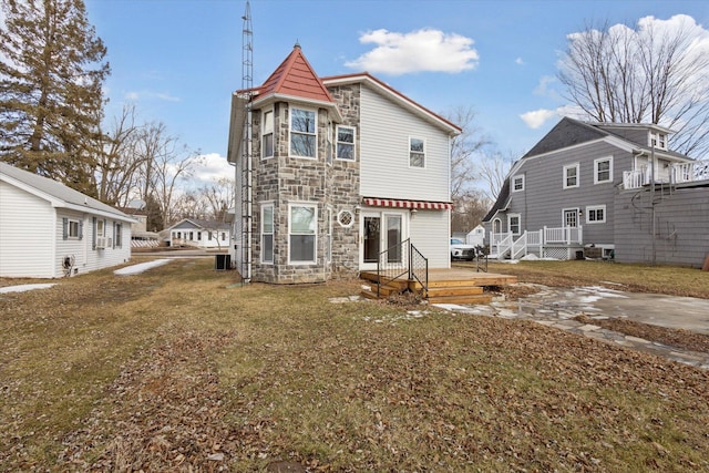 rear view of property with stone siding, a lawn, and a deck