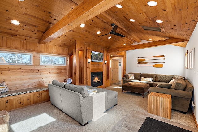 living area with vaulted ceiling with beams, wooden ceiling, wooden walls, and a glass covered fireplace