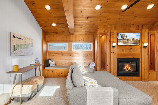 carpeted living room with vaulted ceiling with beams, wood walls, wood ceiling, and a glass covered fireplace