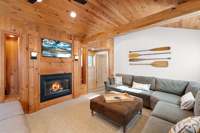 living room featuring a glass covered fireplace, wooden ceiling, light carpet, and wooden walls