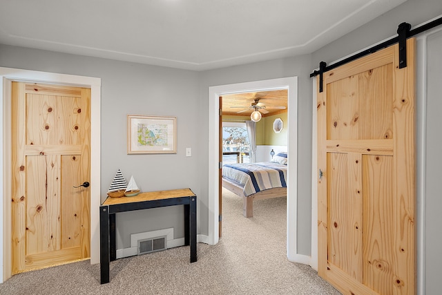 corridor with carpet, a barn door, visible vents, and baseboards