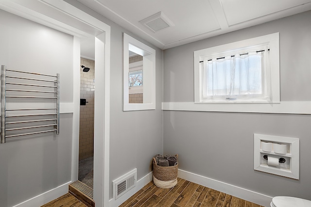 clothes washing area featuring dark wood-style floors, baseboards, visible vents, and radiator heating unit