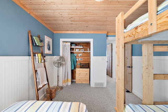 carpeted bedroom featuring a wainscoted wall, wood ceiling, visible vents, and a closet