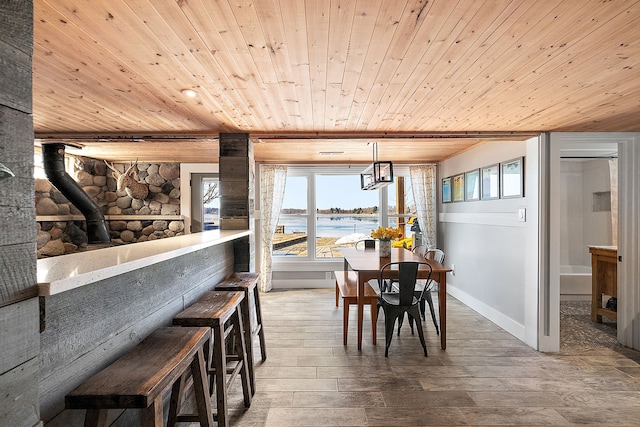 dining area with a water view, a wood stove, wood ceiling, and wood finished floors