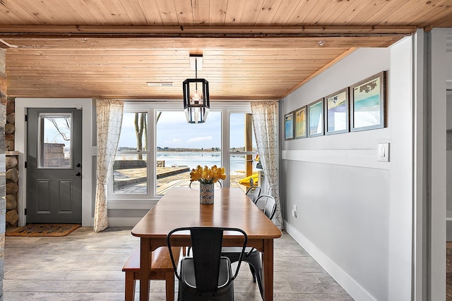 dining area featuring baseboards, wooden ceiling, light wood-style flooring, beamed ceiling, and a water view