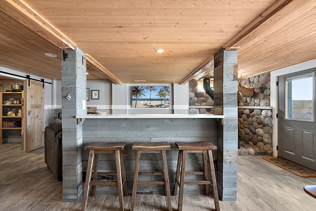 kitchen with wood finished floors, wood ceiling, a breakfast bar area, and a barn door