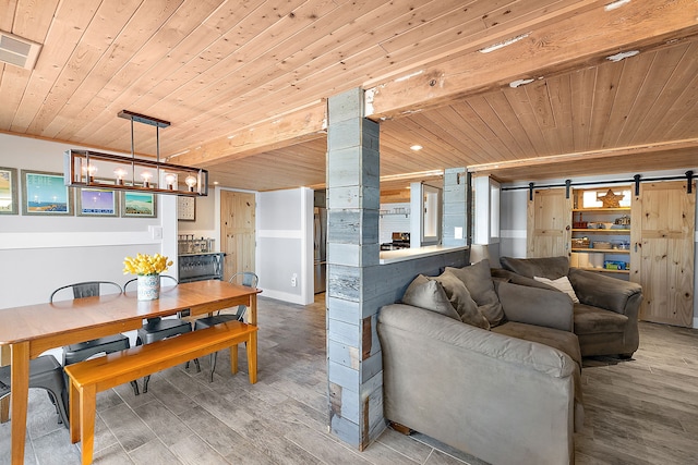 dining area with wood ceiling, a barn door, visible vents, and wood finished floors