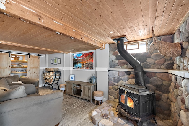 living room with a barn door, wood ceiling, wood finished floors, a wood stove, and beam ceiling