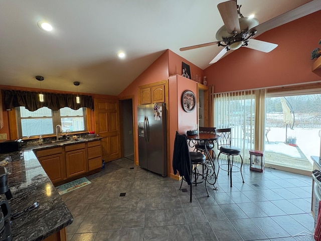 kitchen with a sink, brown cabinetry, dark countertops, and stainless steel fridge