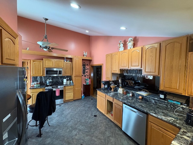 kitchen with tasteful backsplash, dark stone counters, lofted ceiling, appliances with stainless steel finishes, and decorative light fixtures