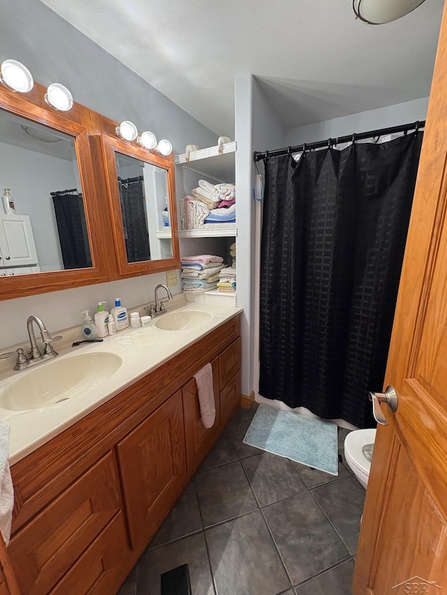 bathroom featuring tile patterned flooring, a sink, toilet, and double vanity