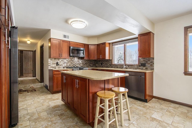 kitchen featuring visible vents, stone finish flooring, stainless steel appliances, light countertops, and backsplash