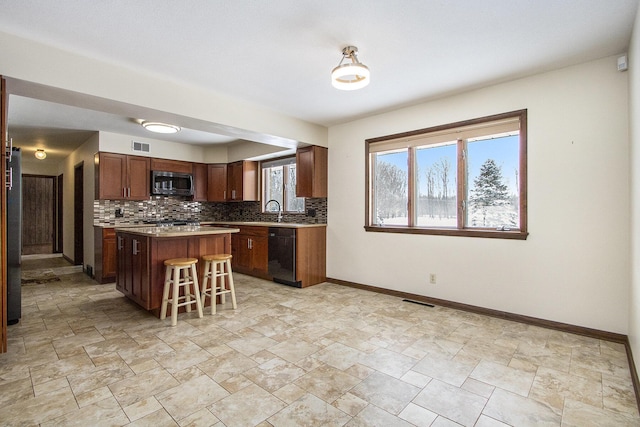 kitchen with tasteful backsplash, black dishwasher, stainless steel microwave, and baseboards